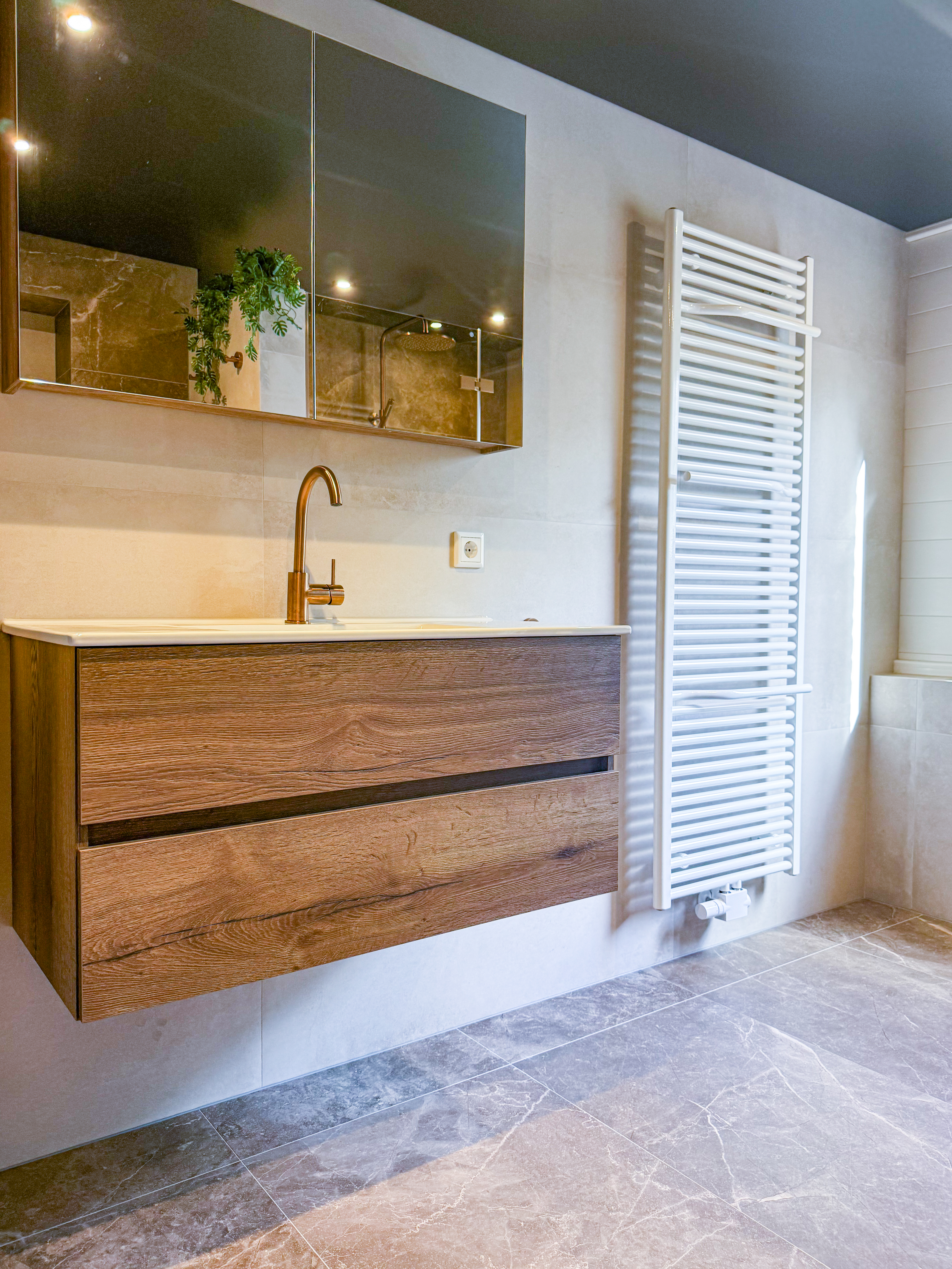 Overzicht van warme badkamer met beige tegels en brons PVD